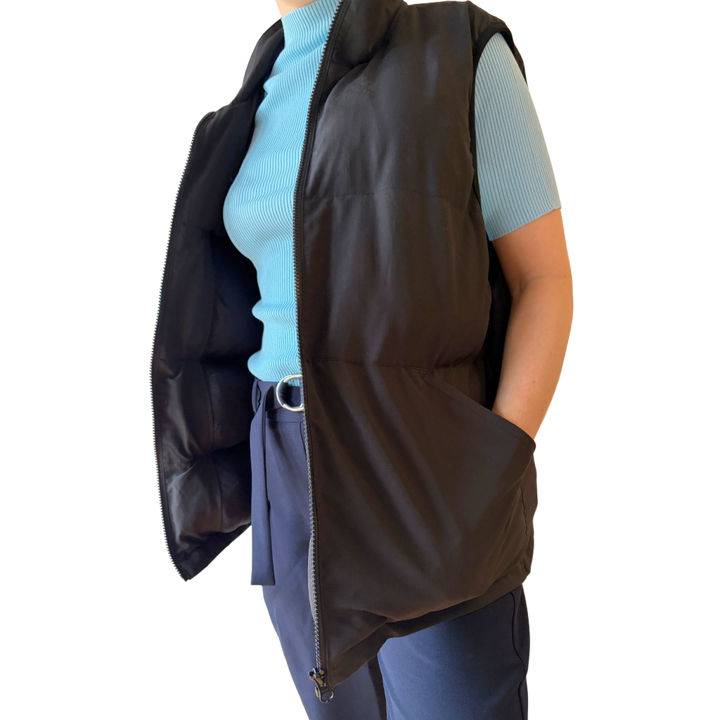 Woman wearing the black Cabin Vest travel vest open, hand in pocket, front view